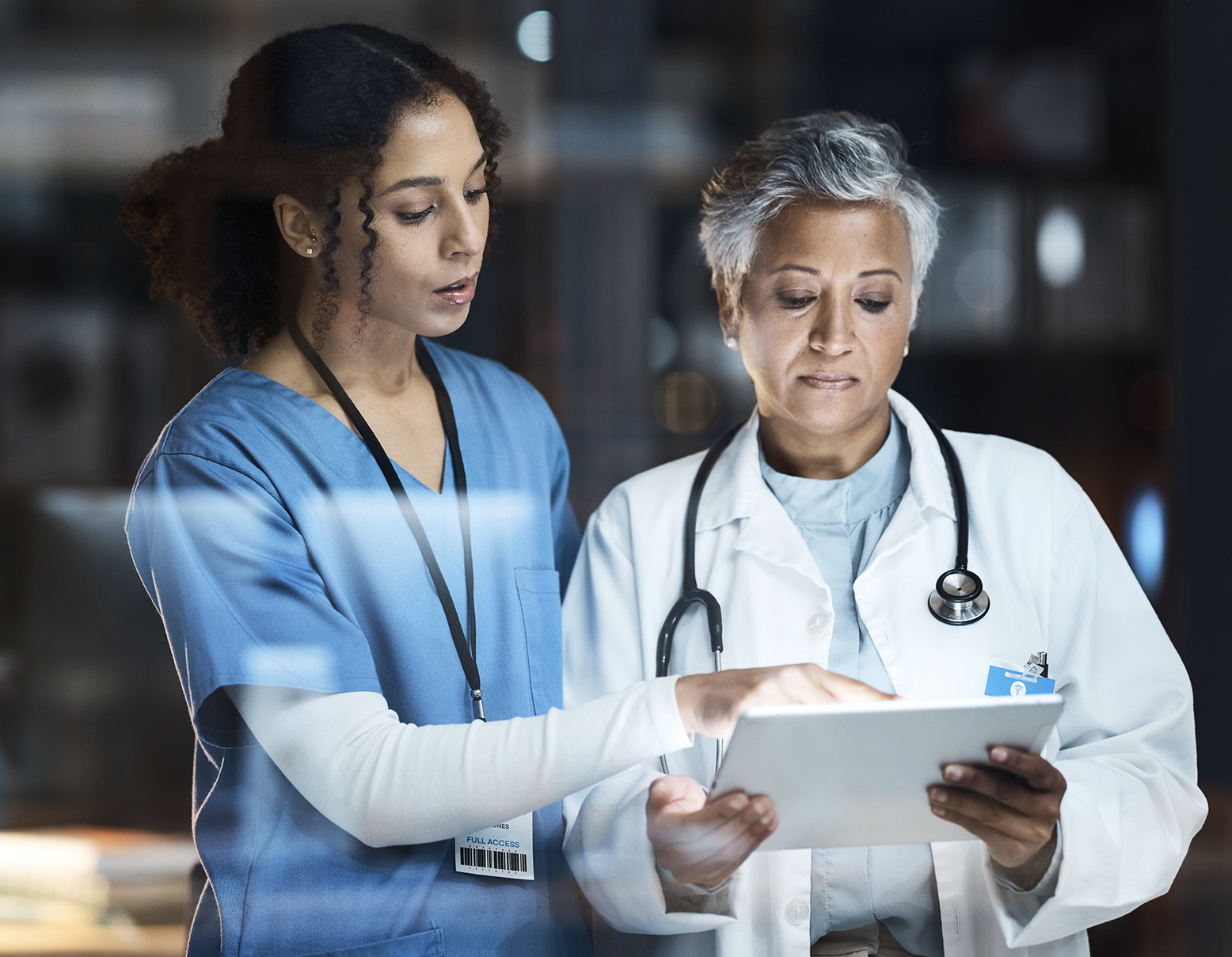 Two healthcare professionals reviewing information on a tablet computer.